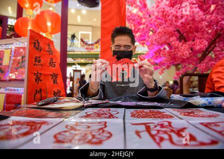 Kuala Lumpur, Malesia. 11th Jan 2022. Un artista di carta-taglio mostra il suo lavoro al Pavilion Paper Art Garden a Kuala Lumpur, Malesia, 11 gennaio 2022. Il Pavilion Paper Art Garden, con la splendida arte tradizionale cinese delle opere di taglio della carta, è stato allestita nelle celebrazioni del prossimo Capodanno cinese. Credit: Chong Voon Chung/Xinhua/Alamy Live News Foto Stock