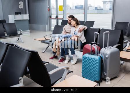 ragazza che dorme in ginocchio di genitori stanchi nella sala dell'aeroporto Foto Stock