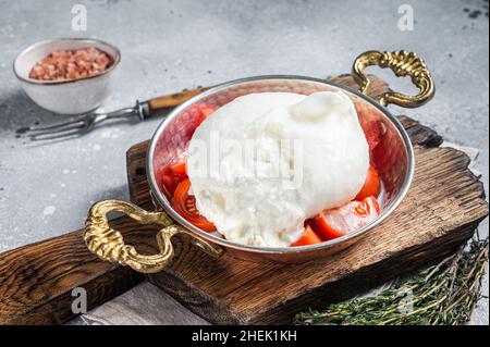 Burrata formaggio italiano a base di panna e latte di bufala o mucca. Sfondo grigio. Vista dall'alto Foto Stock