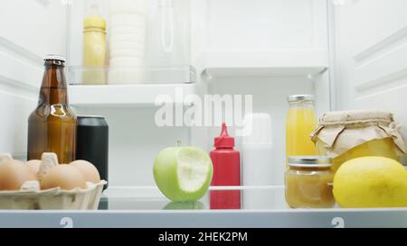 bitate la mela, bottiglie con bevande e salse, limone, miele e purea di frutta in frigo Foto Stock