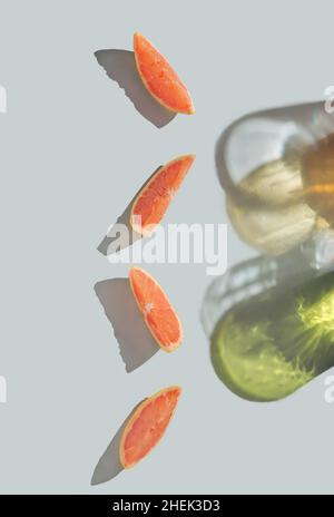 Layout creativo composto da fette di pompelmo e colorate ombre alla moda. Luce solare intensa su sfondo pastello. Foto Stock