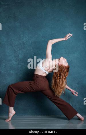 Ballerino di Petitie con capelli rossi auburn che ballano su sfondo grigio Foto Stock