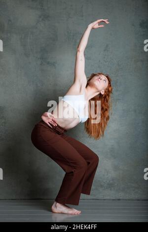 Ballerino di Petitie con capelli rossi auburn che ballano su sfondo grigio Foto Stock