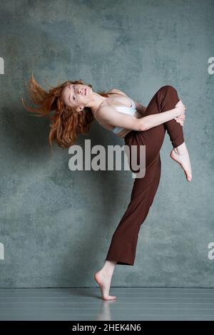 Ballerino di Petitie con capelli rossi auburn che ballano su sfondo grigio Foto Stock