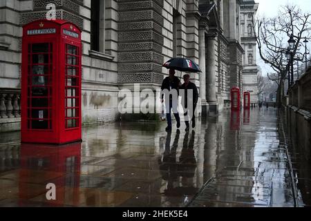 Un paio di passi sotto un ombrello lungo Whitehall a Westminster, centro di Londra. Data foto: Martedì 11 gennaio 2022. Foto Stock