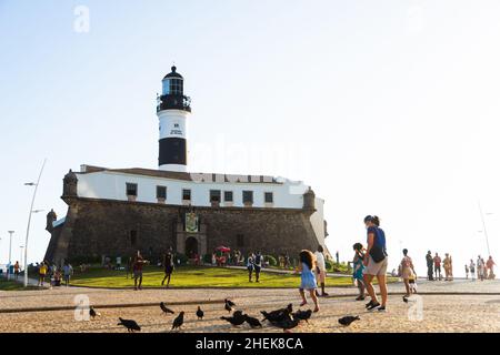 Vista dal basso di Farol da barra in Salvador, con piccioni che mangiano mais a terra e turisti che passeggiando. Foto Stock