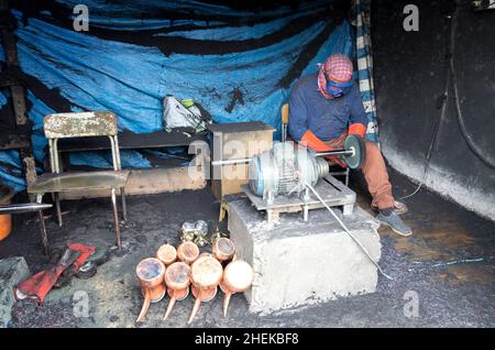 Ushaiqer, Arabia Saudita, 1st gennaio 2022: Uomo che lavora in un laboratorio polveroso, la produzione di caffè arabo pentole Foto Stock