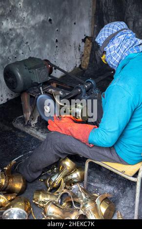 Ushaiqer, Arabia Saudita, 1st gennaio 2022: Uomo che lavora in un laboratorio polveroso, la produzione di caffè arabo pentole Foto Stock