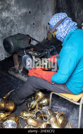 Ushaiqer, Arabia Saudita, 1st gennaio 2022: Uomo che lavora in un laboratorio polveroso, la produzione di caffè arabo pentole Foto Stock