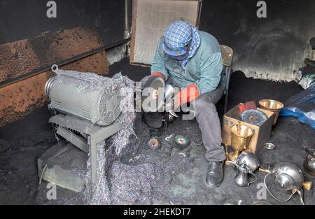 Ushaiqer, Arabia Saudita, 1st gennaio 2022: Uomo che lavora in un laboratorio polveroso, la produzione di caffè arabo pentole Foto Stock