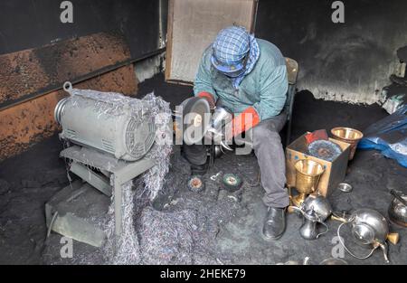 Ushaiqer, Arabia Saudita, 1st gennaio 2022: Uomo che lavora in un laboratorio polveroso, la produzione di caffè arabo pentole Foto Stock