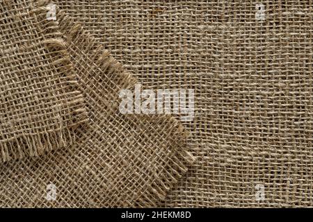 Tela di tela con bordi strappati di fondo. Macrofisura di sacco di canapa, iuta o lino, tessuta grossolanamente. Elemento di design rustico in stile country. Foto Stock