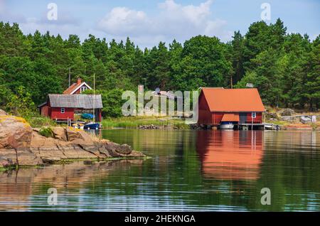 Paesaggio pittoresco con capanne a mare e cottage in legno in tipico rosso svedese ai margini dell'arcipelago di Småland vicino Oskarshamn, Svezia. Foto Stock