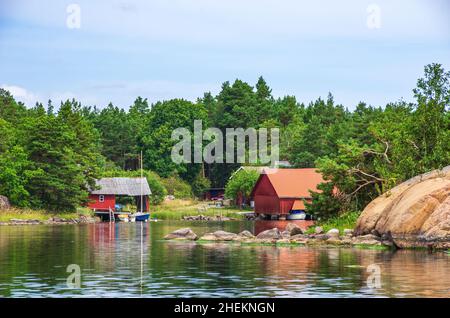 Paesaggio pittoresco con capanne a mare e cottage in legno in tipico rosso svedese ai margini dell'arcipelago di Småland vicino Oskarshamn, Svezia. Foto Stock