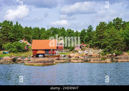 Paesaggio pittoresco con capanne a mare e cottage in legno in tipico rosso svedese ai margini dell'arcipelago di Småland vicino Oskarshamn, Svezia. Foto Stock