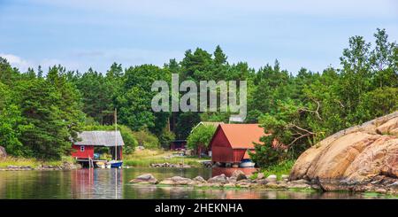 Paesaggio pittoresco con capanne a mare e cottage in legno in tipico rosso svedese ai margini dell'arcipelago di Småland vicino Oskarshamn, Svezia. Foto Stock