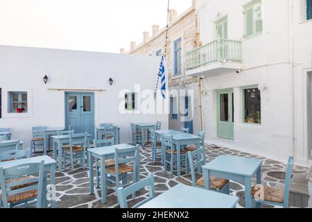 Grecia, Paros isola Naousa porto vecchio. Bar ristorante all'aperto, tavoli e sedie vuoti sul mare Foto Stock