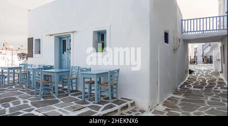 Grecia, Paros isola Naousa porto vecchio. Bar ristorante all'aperto, tavoli e sedie vuoti sul mare Foto Stock