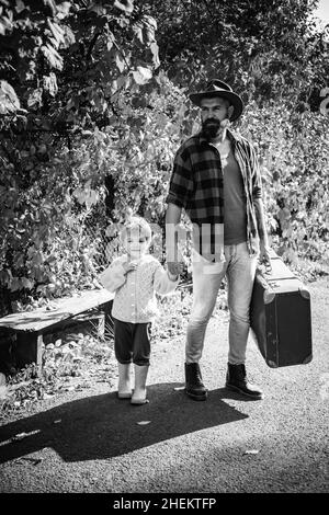 Raccontare storie sui tempi passati. Padre con valigia e suo figlio. Papà sopportato che dice al figlio di viaggiare. Viaggiatori con molta esperienza. Spirito di Foto Stock