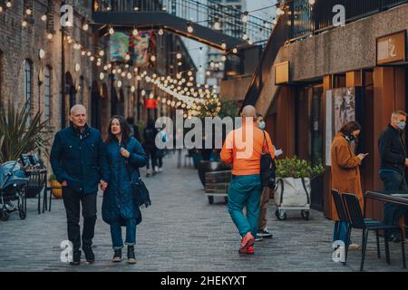 Londra, Regno Unito - 01 gennaio 2022: Persone che camminano sotto le luci a Coal Drops Yard, una destinazione per lo shopping e un luogo di ritrovo gastronomie vicino a King's Cross St Panc Foto Stock