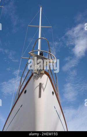 Guardando verso l'alto la prua di una barca a vela, ancora e albero e cielo blu. Foto Stock