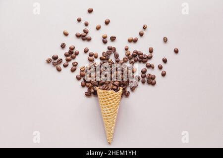 Cialda o cialda cono per gelato con caffè torrefatto marrone in chicchi su sfondo colorato, spazio copia, arte Foto Stock