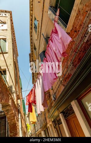 Strada stretta a Venezia con linee di vestiario tra le vecchie case veneziane, Italia Foto Stock