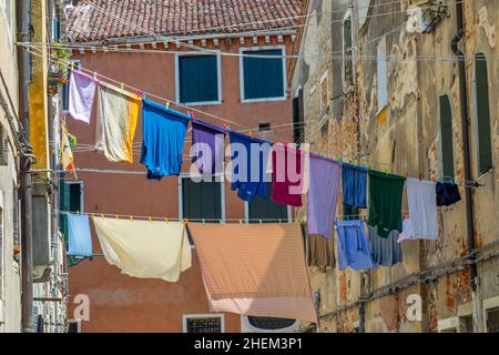 Strada stretta a Venezia con linee di vestiario tra le vecchie case veneziane, Italia Foto Stock