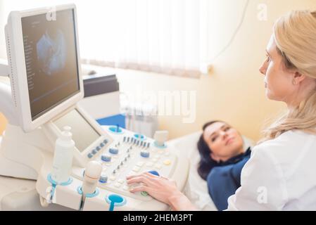 bel ginecologo esamina i dispositivi medici. Il paziente si trova sul lettino Foto Stock