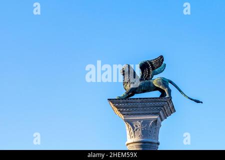 Statua del Leone in Piazza San Marco su sfondo cielo blu, Venezia, Italia. Questo luogo è un'attrazione turistica della città di Venezia. Li alati Foto Stock