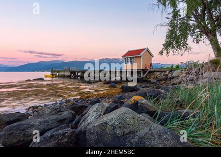 Casa di pescatori in legno giallo a Reine, Lofoten, Norvegia. Tramonto di una giornata di sole nel villaggio sul mare. Molo di legno e bella piccola hou di legno Foto Stock