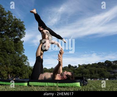 Austin Texas USA, ottobre 17 2021: Uomo e donna che praticano coppie yoga pone a Zilker Park in un autunno Domenica pomeriggio. ©Bob Daemmrich Foto Stock