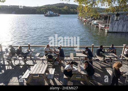 Austin Texas USA, ottobre 27 2021: Studenti e giovani professionisti si trovano al Mozart's Coffee sul lago Austin in un fresco pomeriggio di Austin in autunno. La scena è popolare a causa del suo ampio patio esterno che si affaccia sul lago. ©Bob Daemmrich Foto Stock