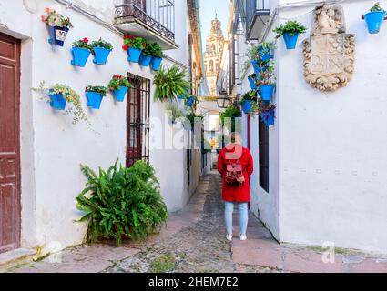 Cordoba, Spagna. Bella ragazza vestita di rosso guardando Calleja de las flores, una famosa strada stretta a Cordoba, Spagna durante il fiore tradizionale Foto Stock
