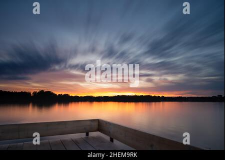 Panoramica tranquilla nube dorata sopra il lago foresta al tramonto. Paesaggio mozzafiato. Lunga esposizione sull'acqua, specchio naturale. Ondulazione su Foto Stock