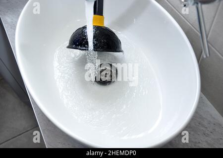 Lavandino ostruito in casa - rimuovere l'ostruzione con il pistoncino del lavandino. Foto Stock