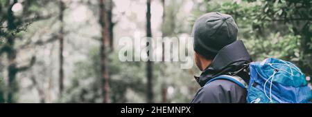 Uomo escursionista che cammina attraverso i boschi nella foresta invernale. Escursioni sport all'aperto stile di vita attivo. Vista dallo zaino posteriore Foto Stock