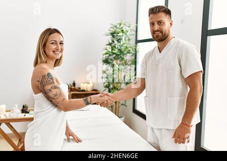 Giovane donna caucasica alla clinica di fisioterapia ottenere massaggio muscolare da terapista professionista. Uomo fisioterapista che agita le mani con il cliente Foto Stock