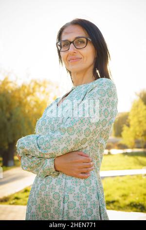 Profilo Vista laterale ritratto di attraente allegro sognante grigio-capelli media-età donna rilassante all'aperto durante la giornata di sole Foto Stock