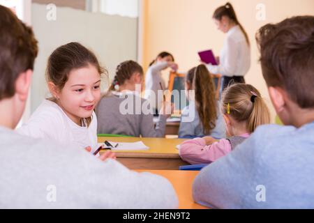 Gli scolari chiacchierano durante la lezione Foto Stock