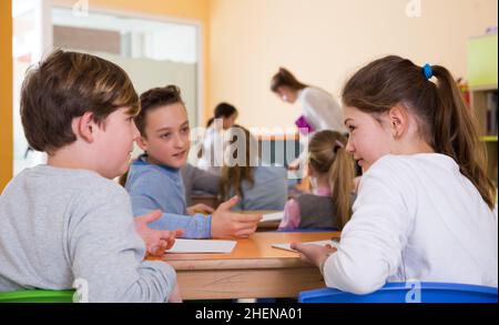 Gli scolari chiacchierano durante la lezione Foto Stock