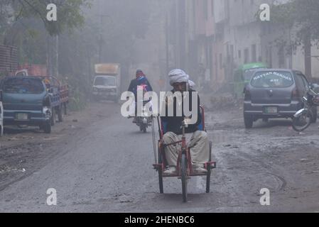 Lahore, Punjab, Pakistan. 11th Jan 2022. Cittadini pakistani, studenti in viaggio durante una fredda e densa mattinata di nebbia a Lahore. I residenti e i pendolari pakistani sono più preoccupati che sorpresi a causa dell'improvviso strato di smog denso che sta causando problemi di respirazione, visibilità e ha anche ostacolato il flusso regolare del traffico; I residenti di Lahore si svegliarono fino ad una densa coperta di smog il Giovedi che ha ridotto la visibilità per i pendolari e ha spinto diverse lamentele di problemi respiratori e angoscia mentale. (Credit Image: © Rana Sajid Hussain/Pacific Press via ZUMA Press Wire) Foto Stock