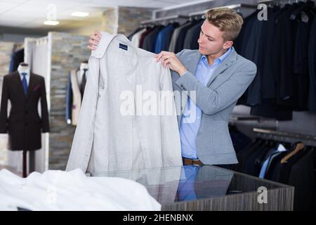 Adulto acquirente maschio in giacca scelta camicia Foto Stock