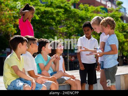 Sorridendo i bambini che chiacchierano e si divertono all'aperto in città Foto Stock