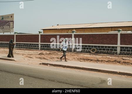 Gibuti, Gibuti - 21 maggio 2021: Una donna di Gibuti e un uomo in abito locale che cammina lungo il marciapiede in tempo caldo a Gibuti. Scatto editoriale in D. Foto Stock