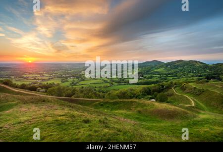 Il sole estivo che sorge sulla campagna del Worcestershire, la luce solare dorata splendente attraverso l'erba lussureggiante sulle colline di Malvern, un percorso lontano Foto Stock