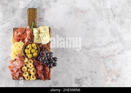 Salumi o antipasti italiani. Assortimento di snack a base di carne e formaggio con olive, uva e miele. Spazio copia, vista sopra Foto Stock