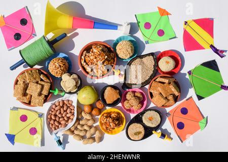 Carta da parati Makar sankranti con piatti speciali del festival Sankranti serviti e consumati come Peanut chikki, tilgul laddu, til baati, frutta bor, arachidi, Foto Stock