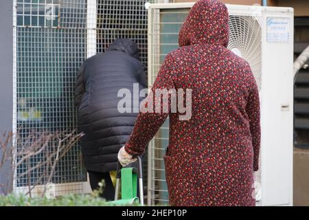 XI'AN, CINA - 12 GENNAIO 2022 - i cittadini acquistano le forniture e prelevano le merci attraverso un buco aperto da una rete di sicurezza della finestra in un supermercato in un comune Foto Stock