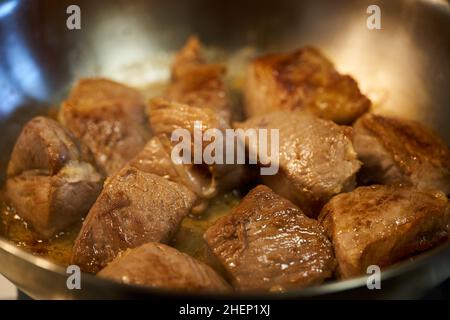 Braciole di maiale (sirloin) che cuocono in una padella d'acciaio inossidabile sulla stufa Foto Stock